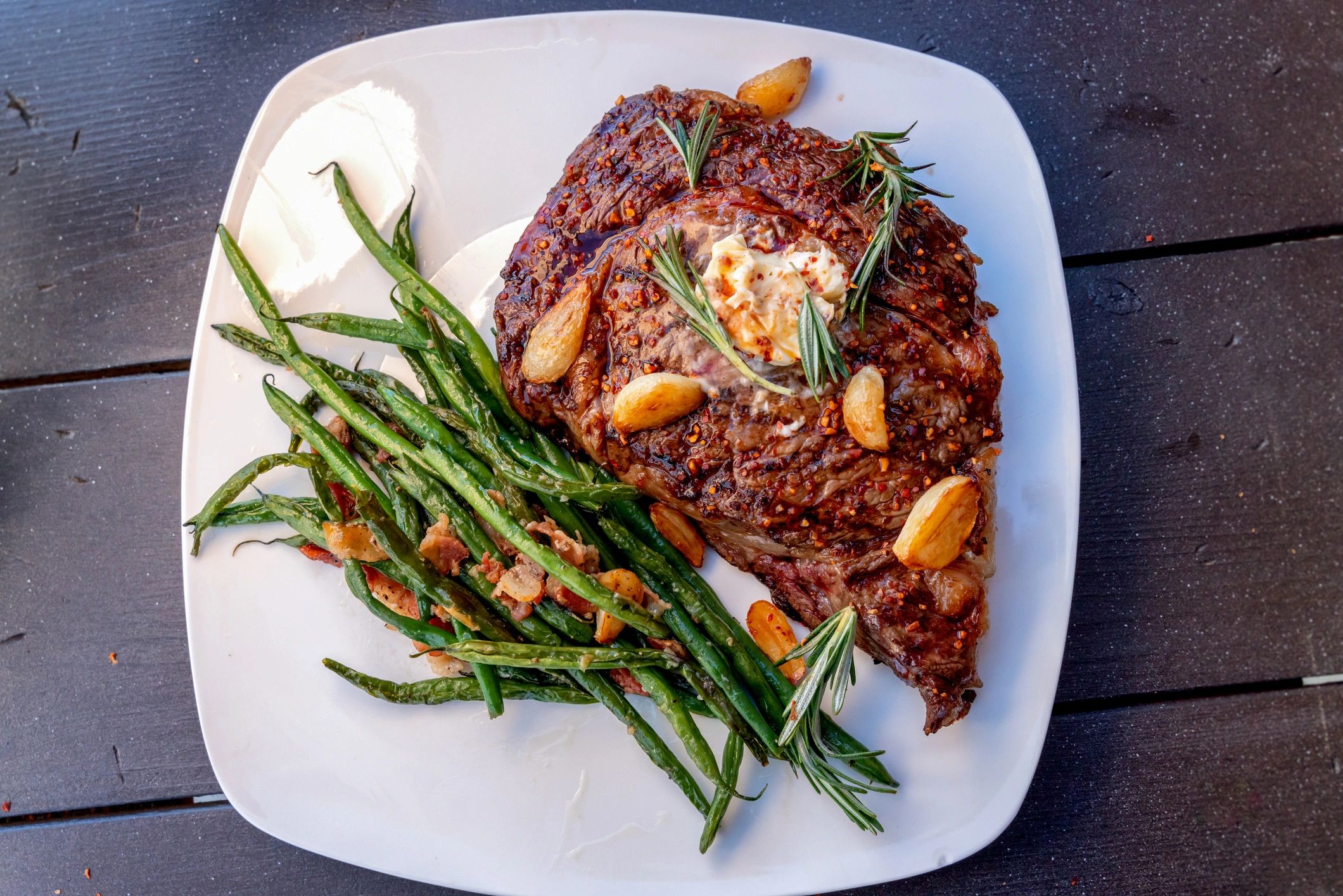Grilled ribeye steak plated with green beans