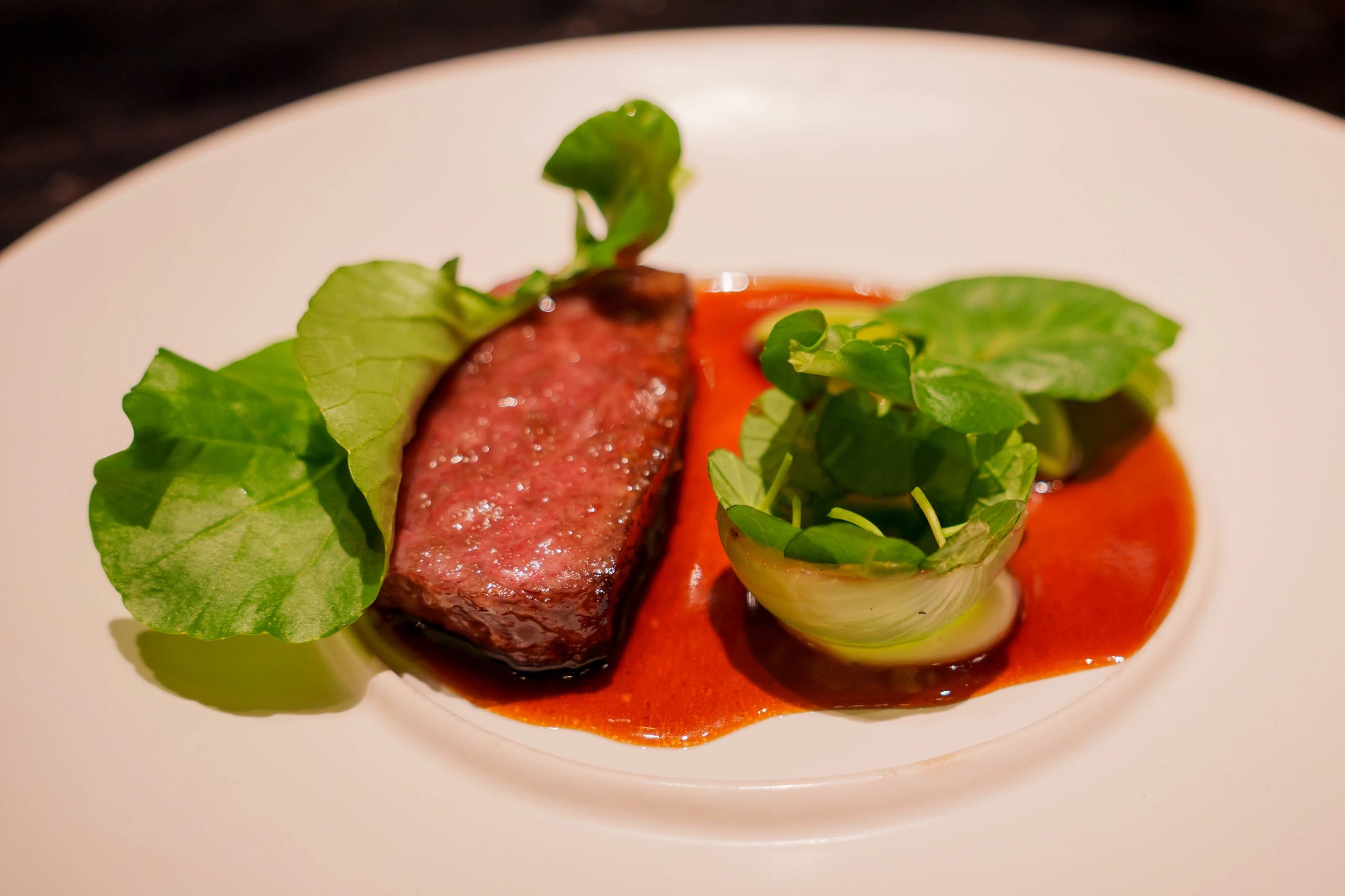 Plated wagyu steak with greens in a fine dining setting